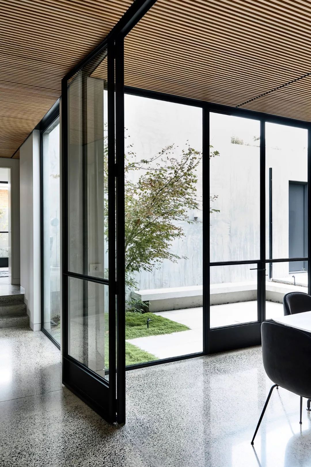 有别于封闭性好的外墙,起居室和走廊面向庭院而建,安装了开阔的玻璃门